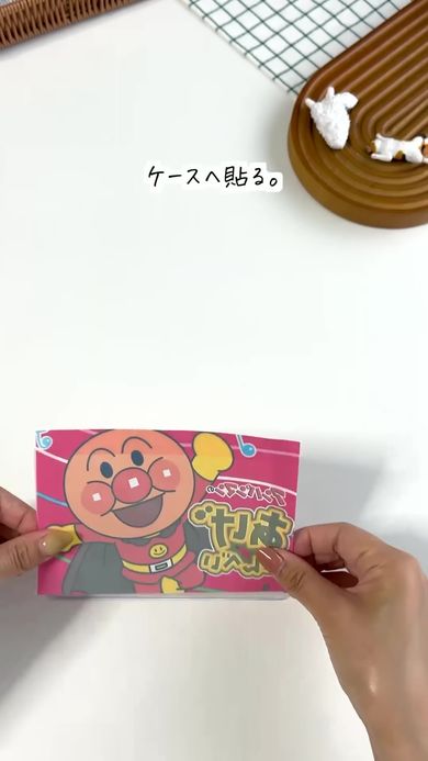 布用強力両面テープで切り抜いた「アンパンマンのあげせんべい」の袋を軟質カードケースに貼る