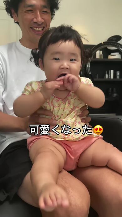 前髪をカットしてかわいく仕上げてもらったことを全身で喜ぶ赤ちゃんと笑顔を浮かべる父親