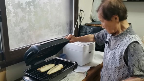 魚の焼き加減を確認する92歳の祖母