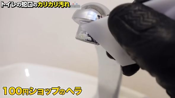 蛇口のカルキ汚れを落とすためプラスチック製のヘラでこする