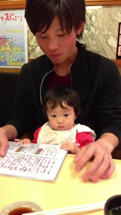 父の膝の上に座って一緒にメニューを見ている娘