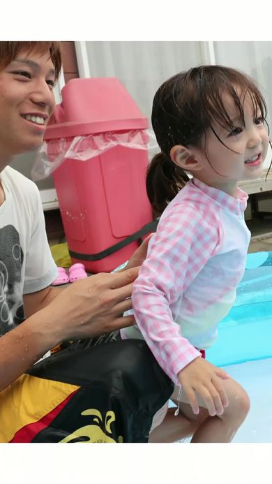 父と一緒に水遊びを楽しんでいる娘