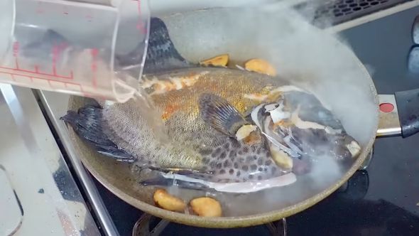 フライパンの上のイシガキダイに白ワインをかける