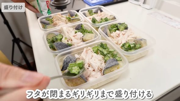 容器内の麺の上にささ身や他の冷凍食品を盛り付ける