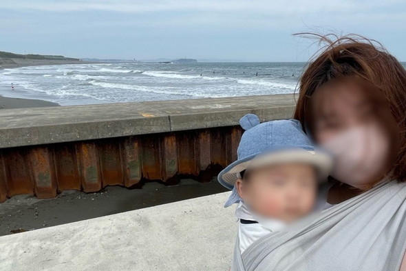 海を背景に記念撮影をするママと赤ちゃん