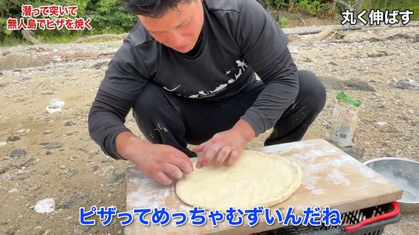 初めてのピザ作りに苦戦しながら生地を伸ばす漁師