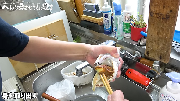 ホラ貝の身に菜箸をさして取り出しているところ