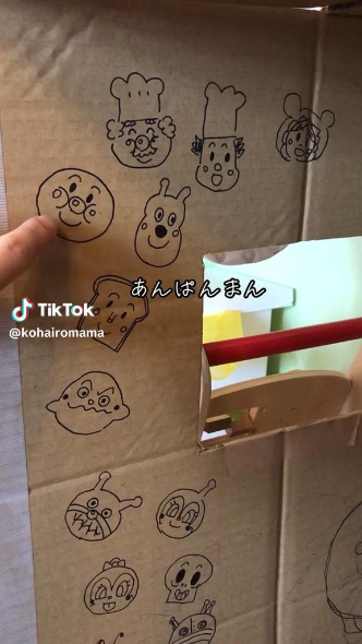 段ボールに描いた絵を指さすママ