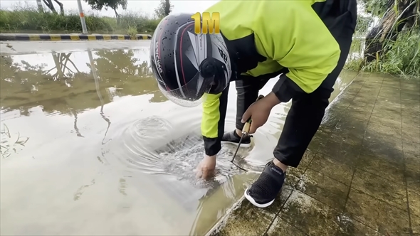 冠水した道路の排水口を掃除する慈善活動