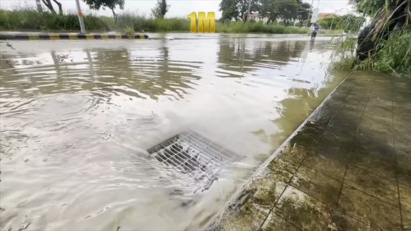 冠水した道路の排水口を掃除する慈善活動