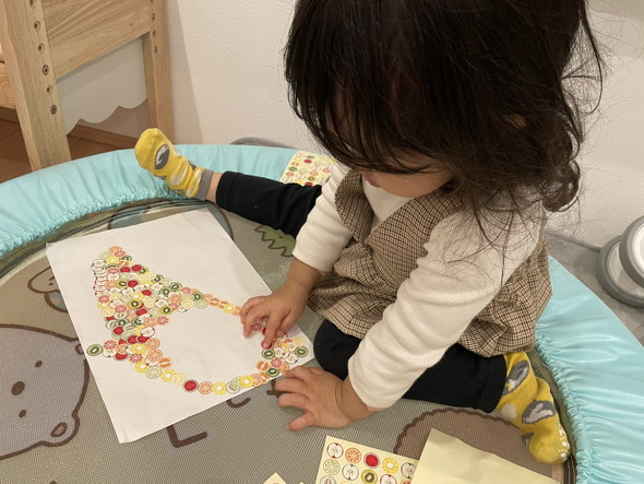 シールを貼ってバナナを作っている2歳の女の子