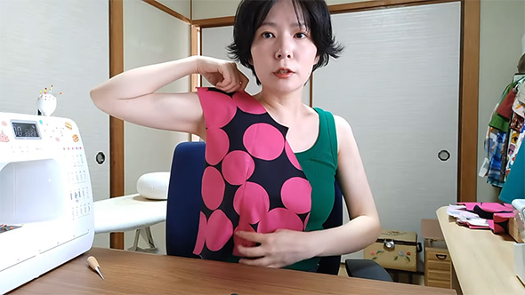 縫い途中の生地を体にあてる女性