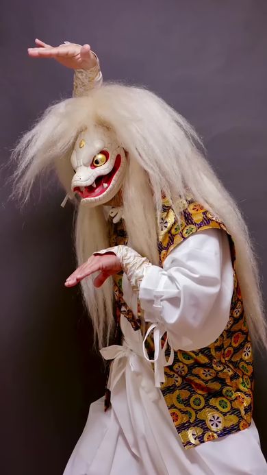 木彫りのヘビの仮面をかぶりヘビらしいポーズを取る