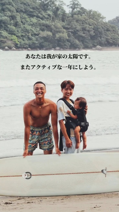 サーフボードを持つ男性と赤ちゃんを抱っこする女性