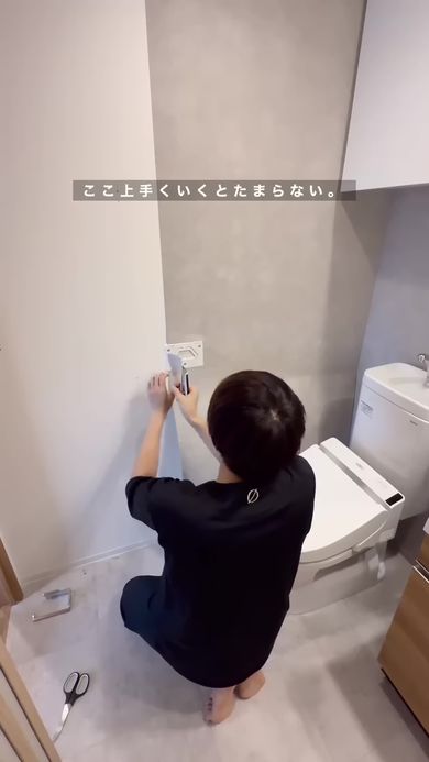 賃貸のトイレをホテルのような作りに変えるため濃いグレーの壁紙シールを貼り一部を切り取る