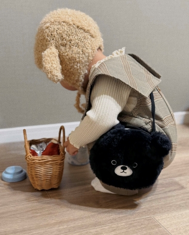 黒いポシェット姿でしゃがむ子ども