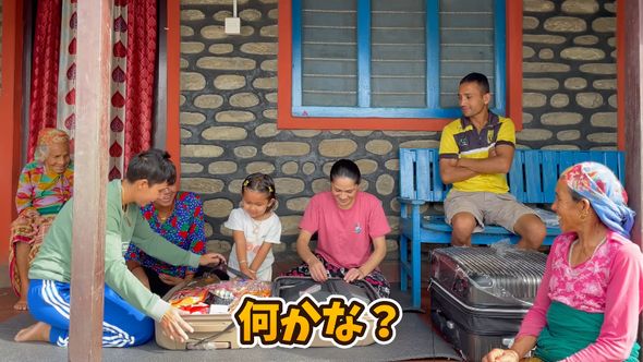 家族が見ている前でお土産が入っているスーツケースを開けるネパール人姉妹