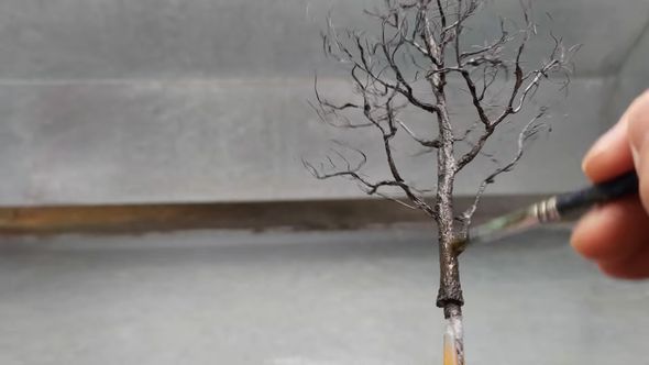 銅線でできたイチョウの木に塗料を塗る