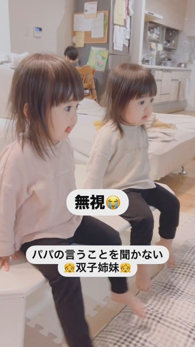 テーブルに座って注意される1歳の双子姉妹