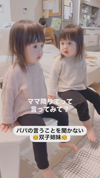 テーブルに座って注意される1歳の双子姉妹