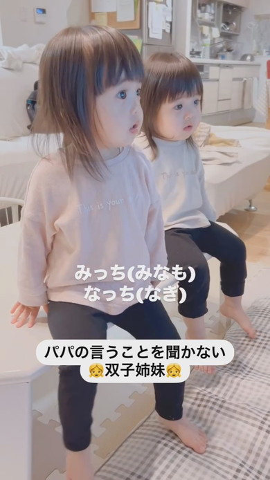 テーブルに座って注意される1歳の双子姉妹