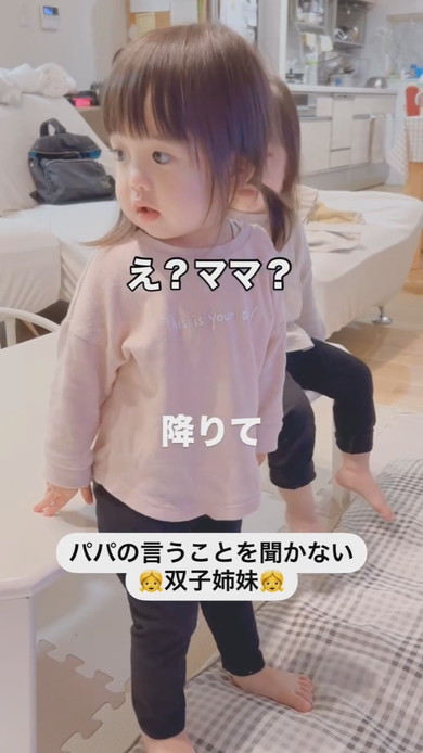 テーブルに座って注意される1歳の双子姉妹