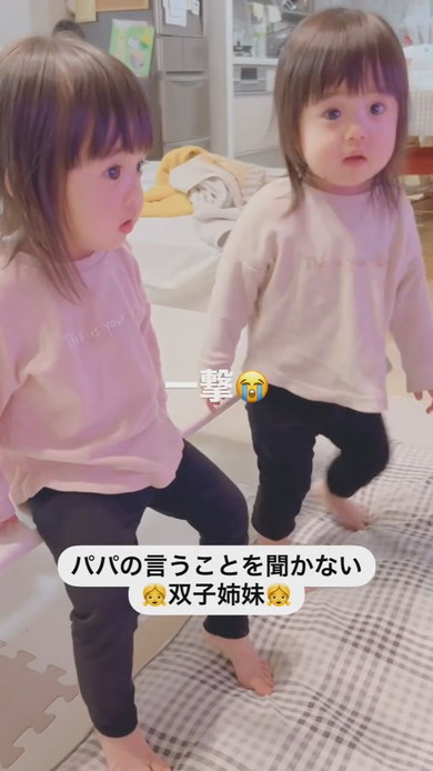 テーブルに座って注意される1歳の双子姉妹