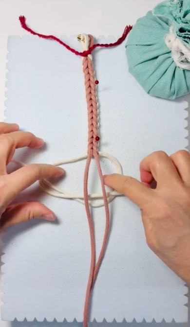 白とピンクのひもを編みこむ