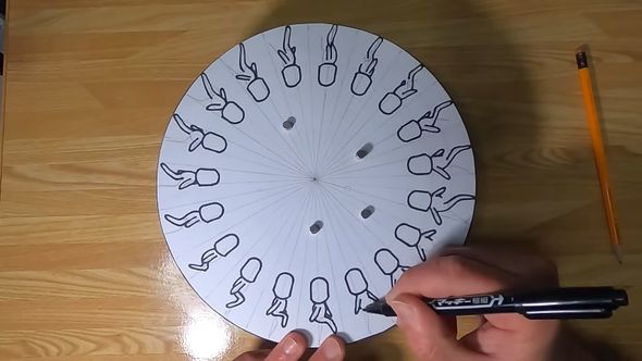 円盤を回しながら油性ペンで歩いている人を描く