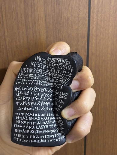 ゴム製のロゼッタ・ストーンのおもちゃを握りしめる