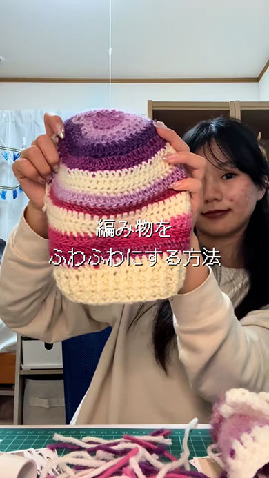 ニットの帽子を掲げる女性