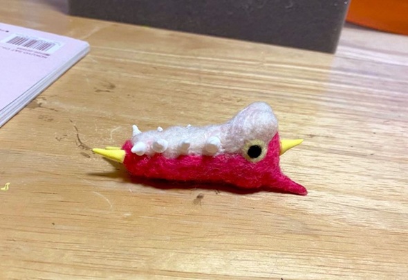 羊毛フェルトで作ったケムッソがあお向けになっている姿