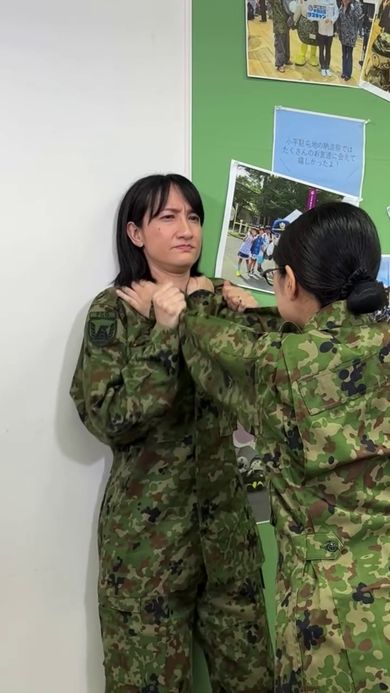 犯人役の同僚に襟の近くを押さえられて動けない女性自衛官