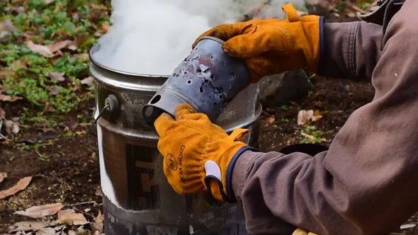 ぬかくど用のペール缶から立ちのぼる白い煙とボロボロの火起こし器