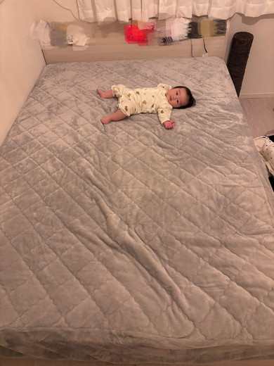 シーツがセッティングされたベッドに寝転がる赤ちゃん