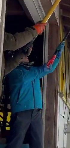 兵庫県北部で屋根から長く伸びた雪の塊を下ろす様子