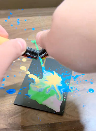 書けなくなったインク入りペンを黒板の上にかざしている様子