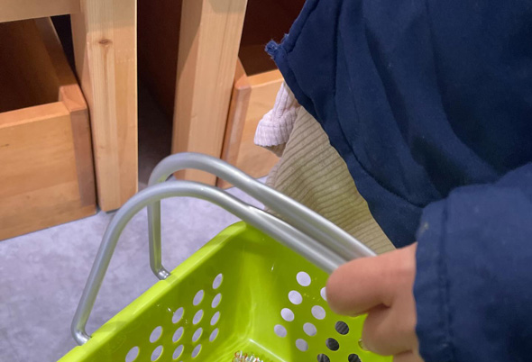 駄菓子やコーナーでカゴを持つ人