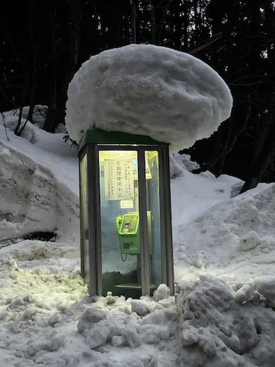 雪に埋もれつつある公衆電話ボックス