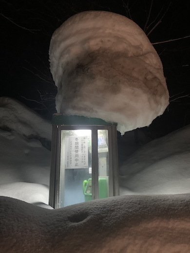 雪に埋もれた公衆電話ボックス