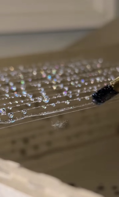 レジンを透明糸に塗っているところ