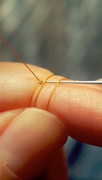 指の上で細い糸を編む様子