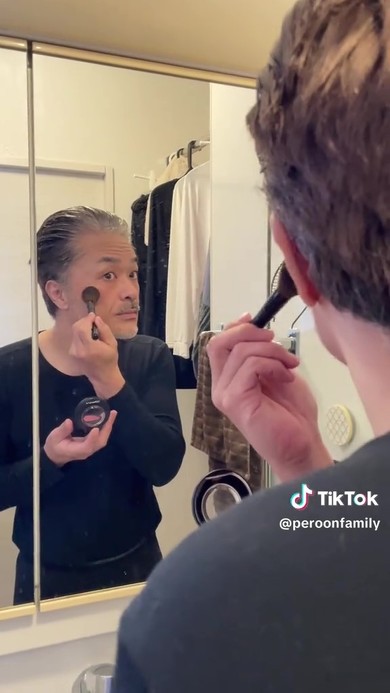 鏡を見ながらメイクする男性