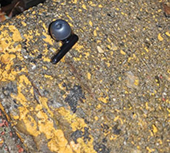 下水蓋の近くに黒いワイヤレスイヤフォンが落ちているところをアップにしたところ