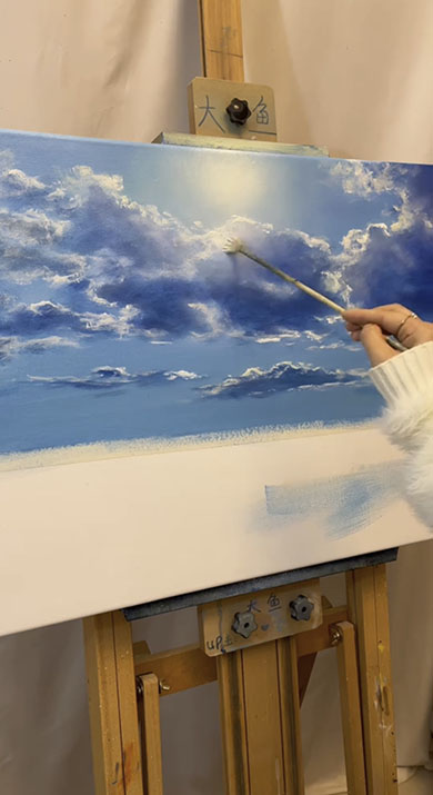 白いキャンパスに青空の様子が描かれているところ。キャンパス中央上部に太陽があり、その周りを雲が漂っている