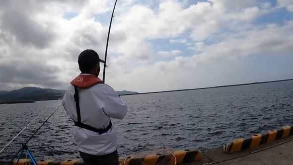 魚を釣るべく巻き取る夫