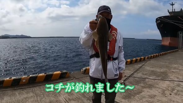 フィッシュグリップでコチをつかんでいる夫