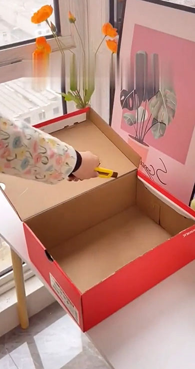 靴の外箱に切り込みを入れ、フタと箱本体に分けている様子