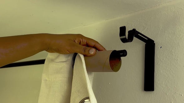 カーテンのポールにトイレットペーパーの芯を通す様子