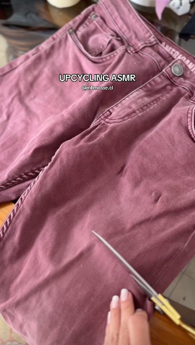 机に置かれたデニムパンツにハサミを入れるところ